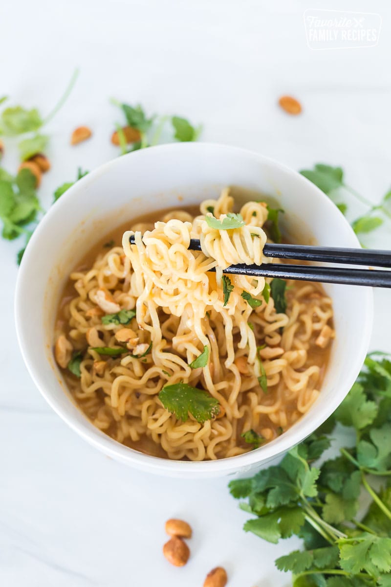 Chopsticks pulling up ramen noodles from a bowl.