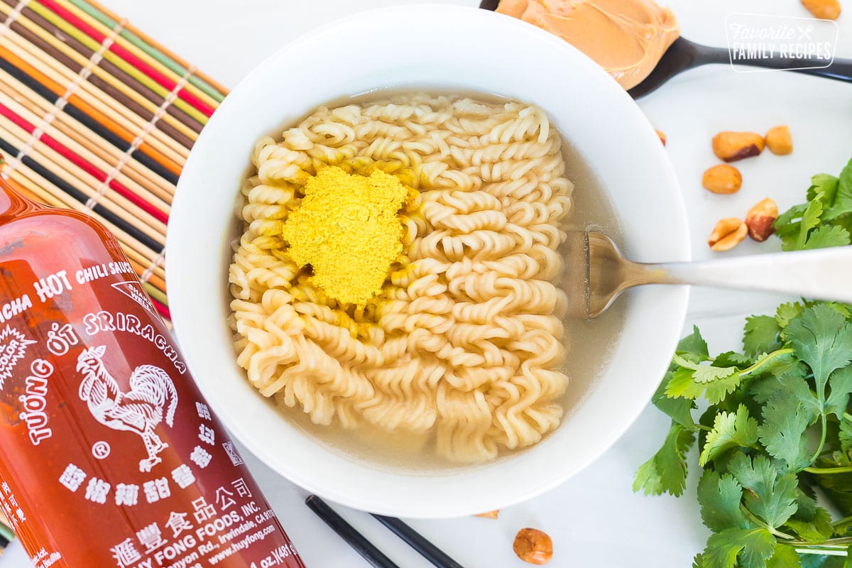 A bowl of cooked ramen with seasoning mix over the top.