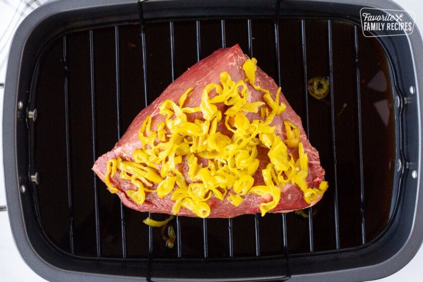 Roasting pan with a Roast topped with peperoncini for Italian Beef Sandwiches.