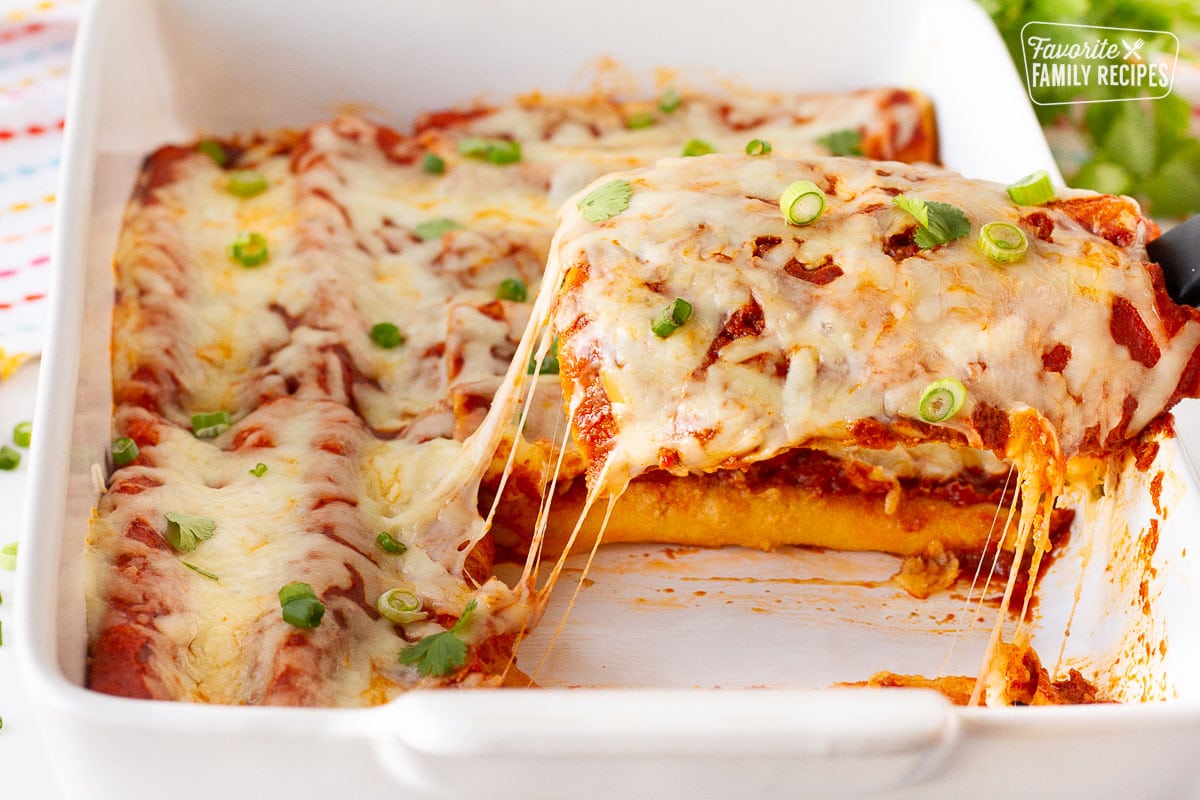 Spatula grabbing Easy Cheese Enchiladas with the cheese pulling up.