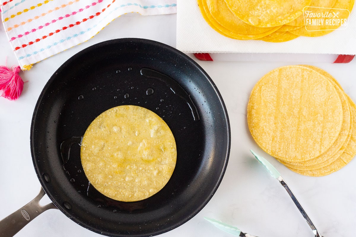 Frying corn tortillas in a pan of oil for Easy Cheese Enchiladas.