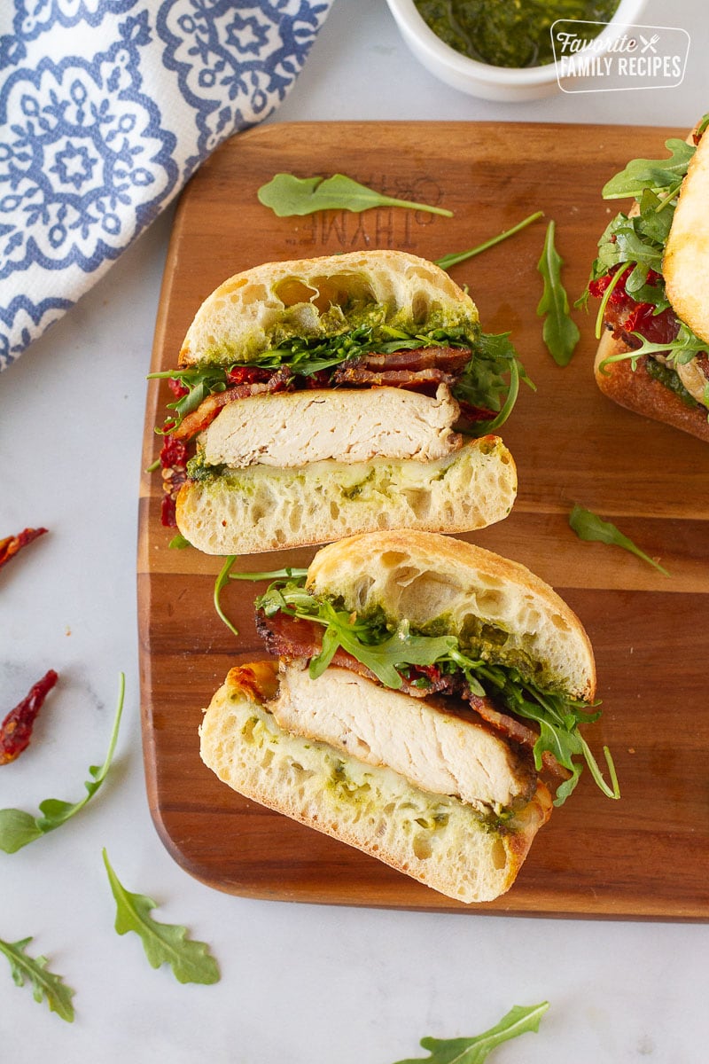 Chicken Pesto Sandwich cut in halves on a cutting board.