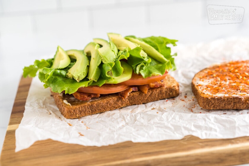 Toast with bacon, tomatoes, cucumbers, lettuce, avocado on top.