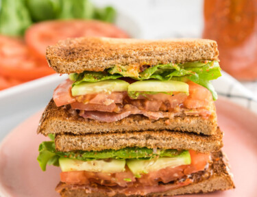 a blt sandwich cut in half and stacked on a plate