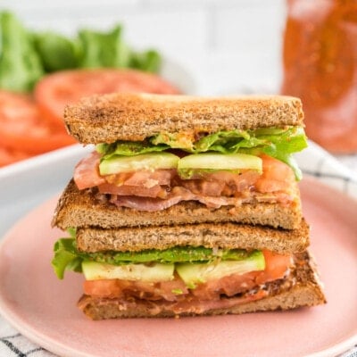 A BLT sandwich cut in half and stacked on a plate.