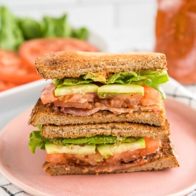 A BLT sandwich cut in half and stacked on a plate.