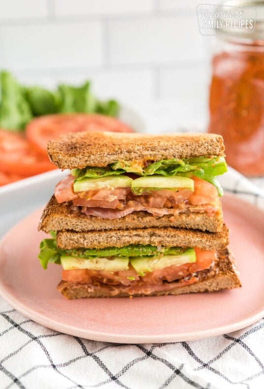 a blt sandwich cut in half and stacked on a plate