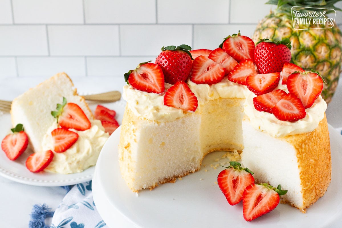 Angel Food Cake with pineapple whip topping and decorated with fresh sliced and whole strawberries.