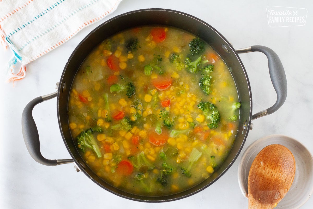 Pot of corn, broccoli, carrots potatoes and broth to make Creamy Vegetable Soup.