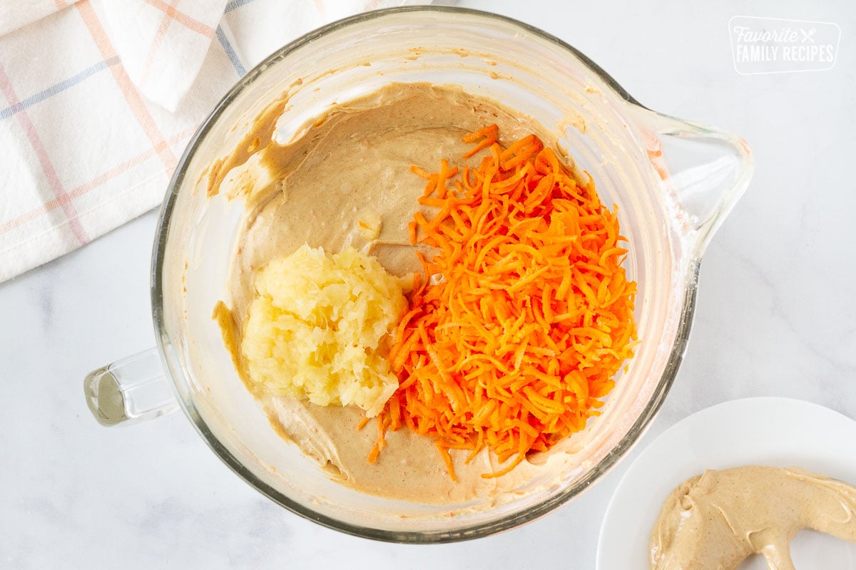 Mixing bowl with Carrot Bundt Cake batter with shredded carrots and crushed pineapple on top.