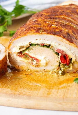 Stuffed Pork Loin with cream cheese, bacon, spinach and peppers on a cutting board.