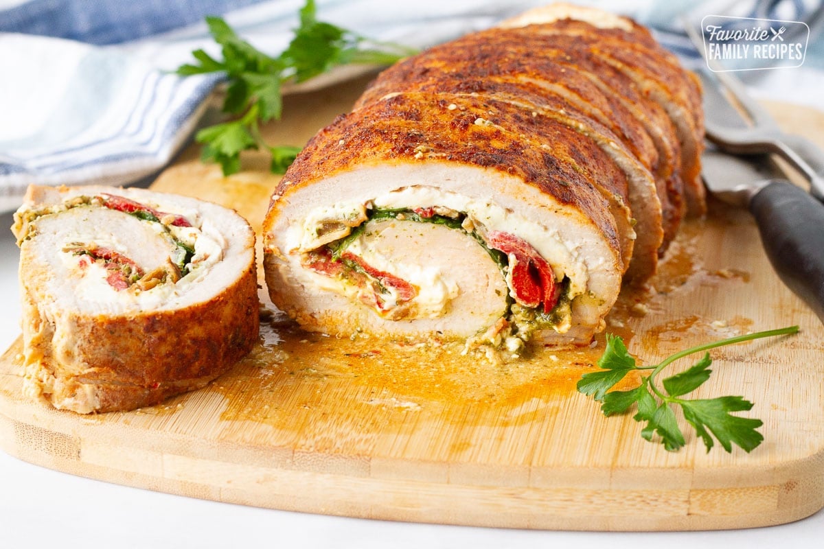 Stuffed Pork Loin with cream cheese, bacon, spinach and peppers on a cutting board.