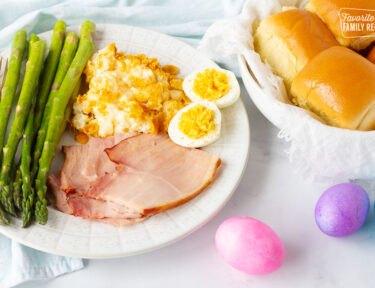 Easter Dinner Ideas with Homemade Rolls, crockpot ham, cheesy funeral potato casserole, and asparagus. Side of deviled eggs.