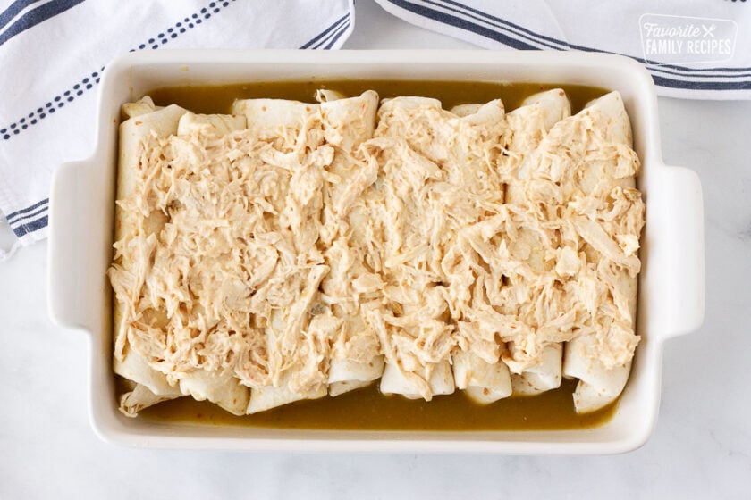 Baking dish topped with chicken filling for Sour Cream Chicken Enchiladas.