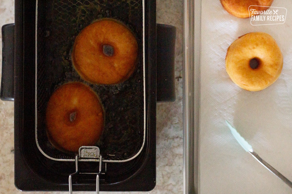 Frying Homemade Donuts next to some fried homemade donuts on paper towels.