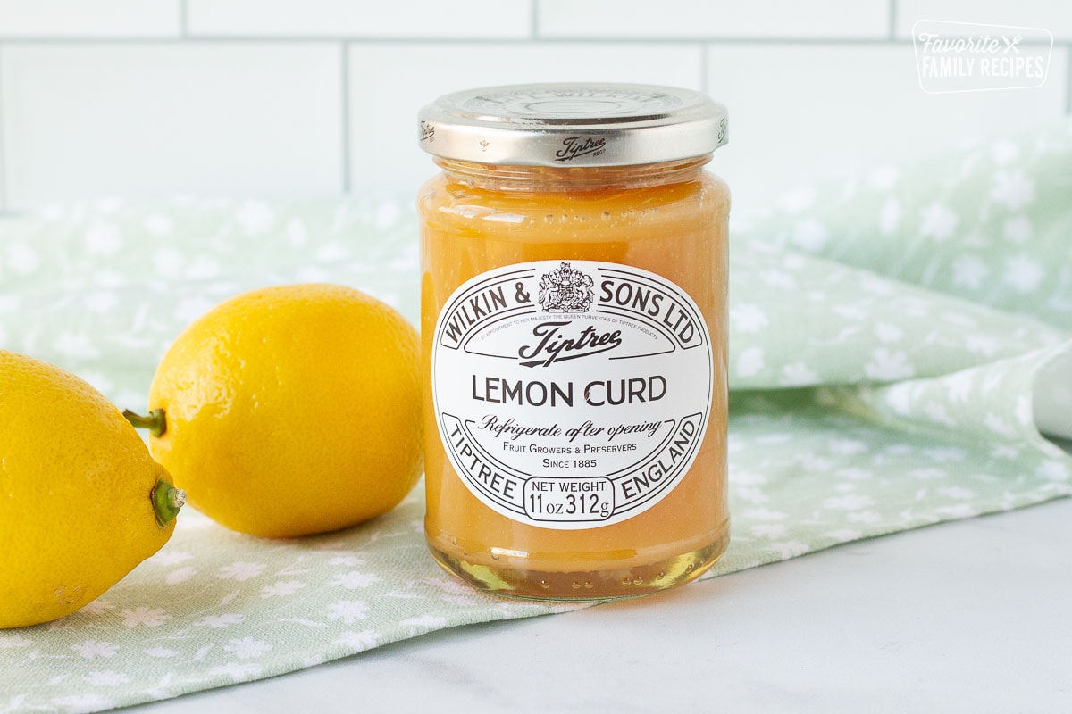Jar of Lemon Curd with two fresh lemons for Lemon Cupcakes frosting.
