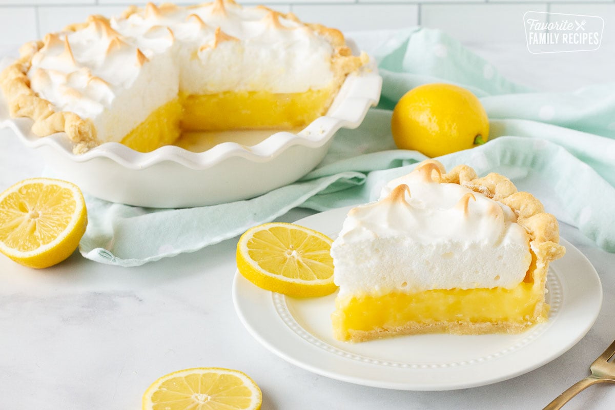 Slice of Lemon Meringue Pie on a plate next to pie in a baking dish.