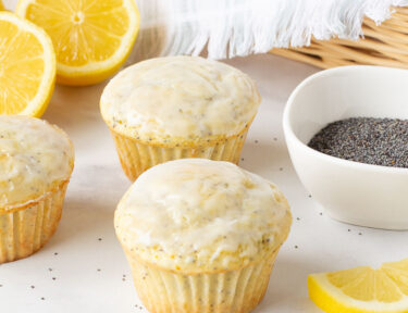 Three Lemon Poppy Seed Muffins in front of a basket of muffins.