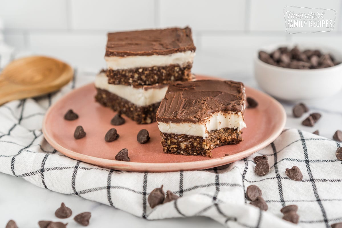 Three Nanaimo Bars on a plate with a bite taken out of one