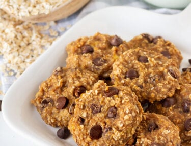 Plate of Healthy Oatmeal Cookies with a glass of milk and oats on the side.