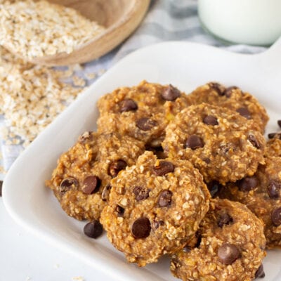 Plate of Healthy Oatmeal Cookies with a glass of milk and oats on the side.