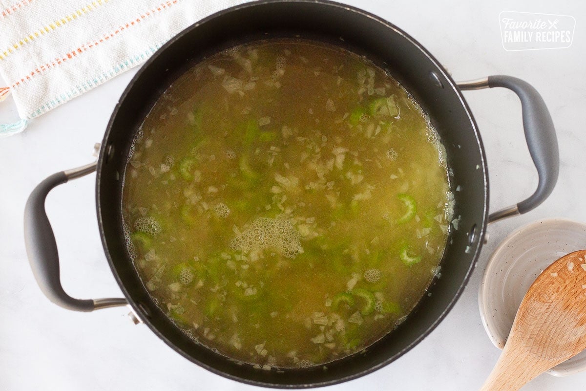 Pot of broth, onions and celery to make Creamy Vegetable Soup.