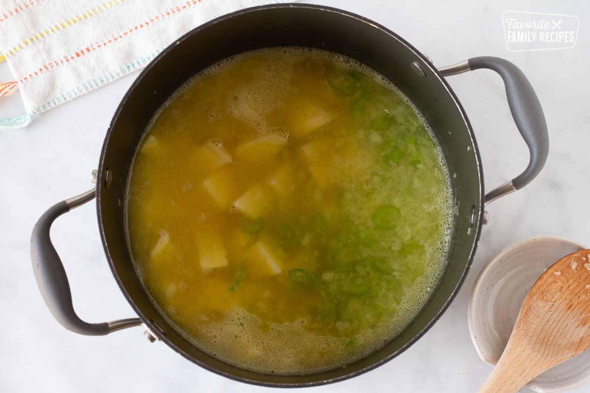 Pot of broth, potatoes, celery and onion to make Creamy Vegetable Soup.