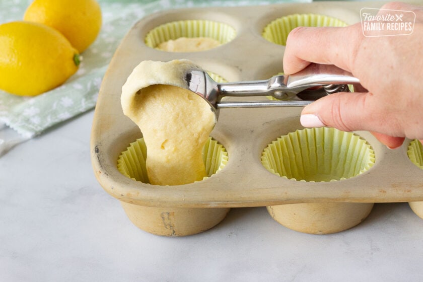 Cookie scoop pouring Lemon Cupcake batter in the cupcake liners.