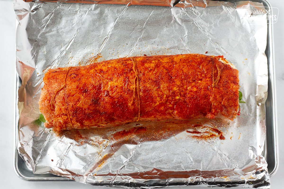 Baking sheet lined with foil with a raw seasoned Stuffed Pork Loin.