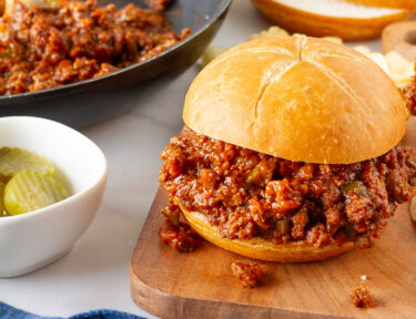 Homemade Sloppy Joe next to a skillet of filling and extra sliced rolls.