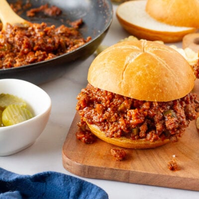 Homemade Sloppy Joe next to a skillet of filling and extra sliced rolls.