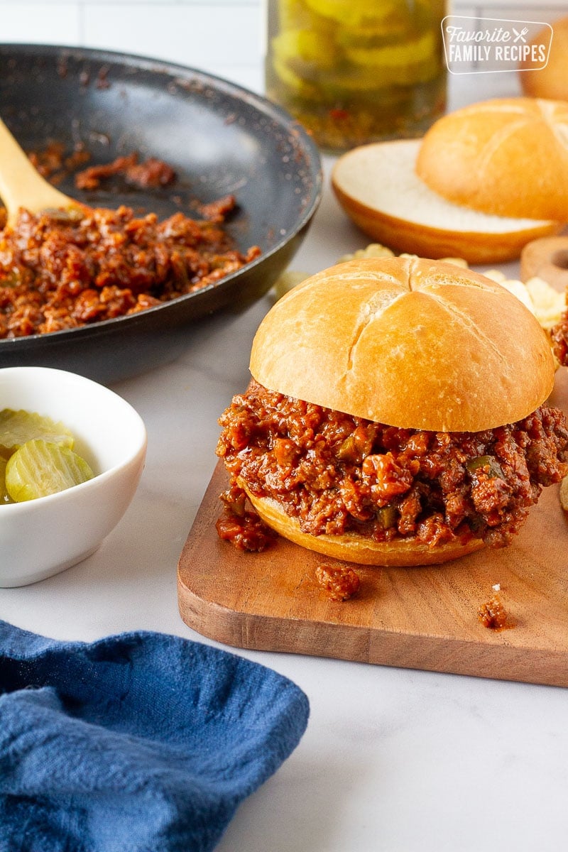 Homemade Sloppy Joe next to a skillet of filling and extra sliced rolls.