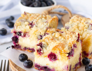 Three slices of Blueberry Coffee Cake. Fresh blueberries on the side.