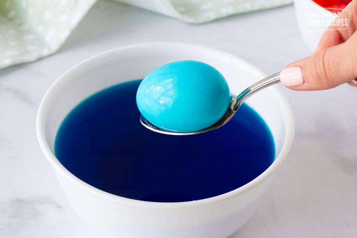 Hand holding spoon with dyed egg for Easter Bread.