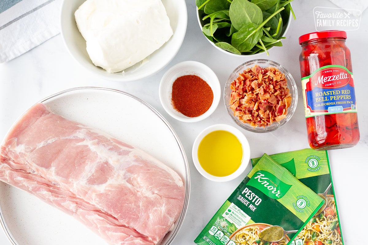 Ingredients to make Stuffed Pork Loin including, Pork Tenderloin, cream cheese, spinach, bacon, paprika, olive oil, pesto sauce mix and roasted red bell peppers.