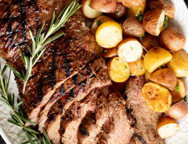 Tri Tip Roast on a serving platter with potatoes.