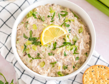 Tuna salad in a white bowl with celery and crackers.