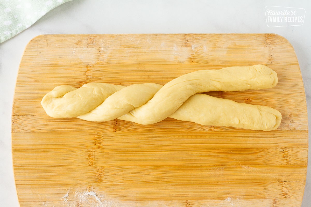 Two dough ropes of Easter Bread twisting together on a cutting board.
