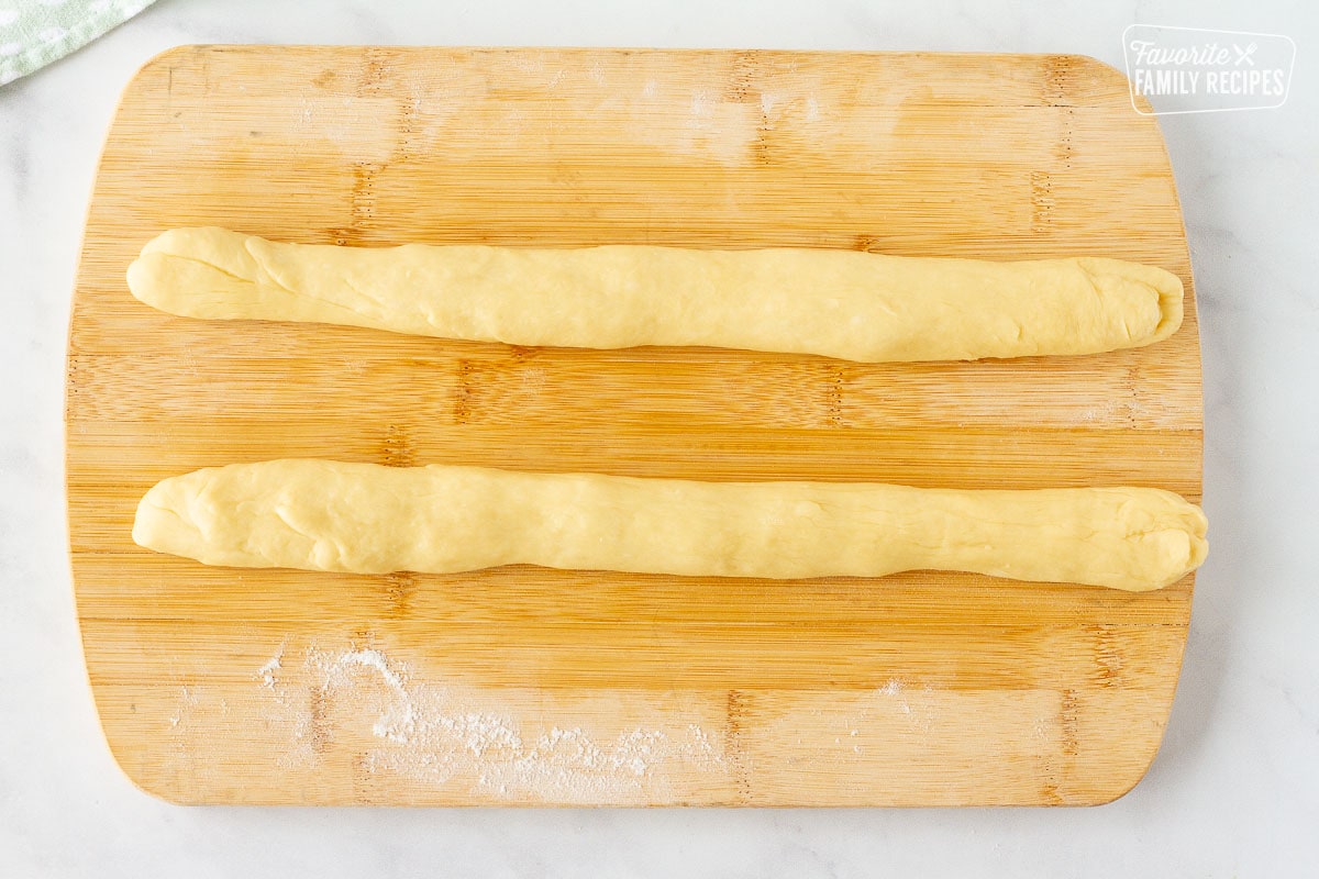Rolled out Easter Bread dough ropes on a cutting board.