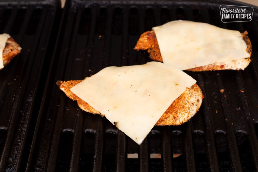 Slices of pepper jack cheese on top of cooked Chicken Tortas on the barbecue.
