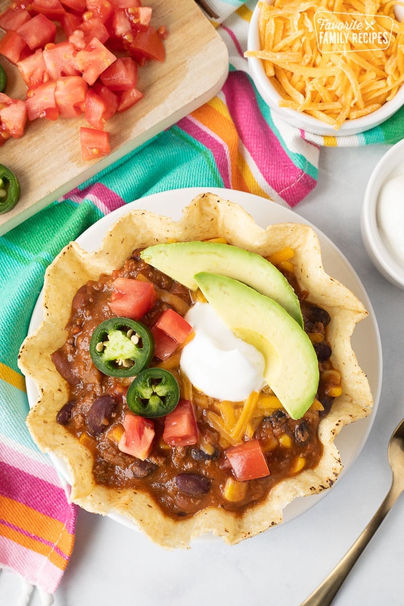 Tostada bowl of Mexican Chili with cheese, sour cream, jalapeños, avocado and tomatoes.