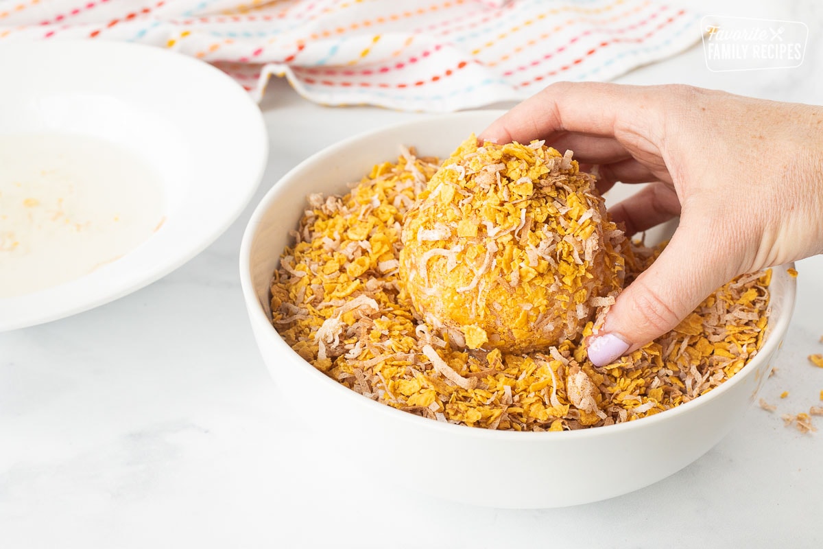Covering ball of ice cream with corn flakes, coconut and cinnamon mixture for Fried Ice Cream.