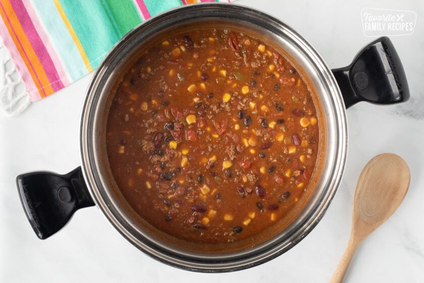 Pot of cooked Mexican Chili with a wooden spoon.