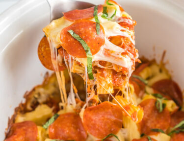 A spoon take a scoop out of crockpot pizza casserole