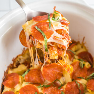 A spoon take a scoop out of crockpot pizza casserole
