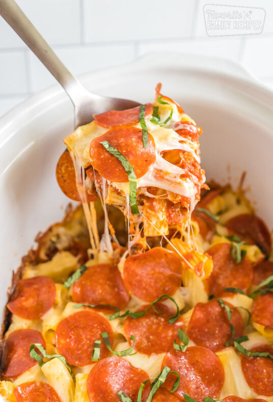 A spoon take a scoop out of crockpot pizza casserole