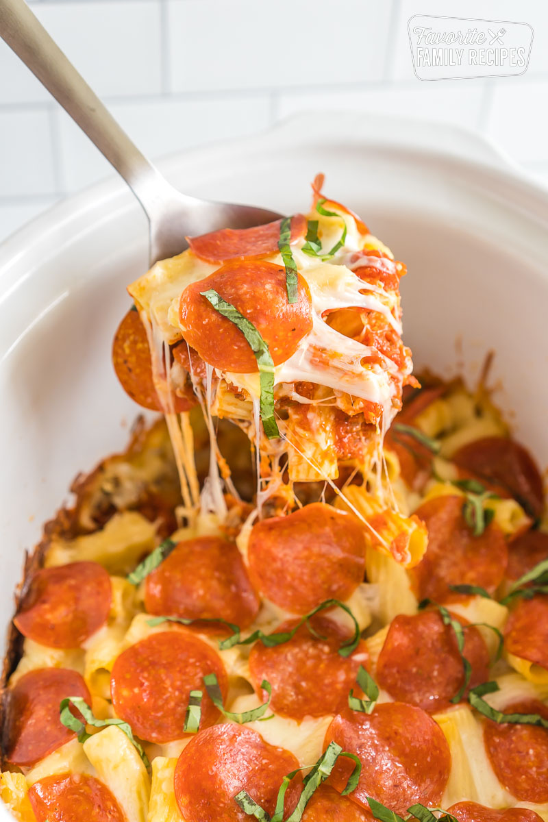 A spoon take a scoop out of crockpot pizza casserole