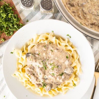 Pot of Easy Beef Stroganoff next to a plate of Beef Stroganoff over noodles.