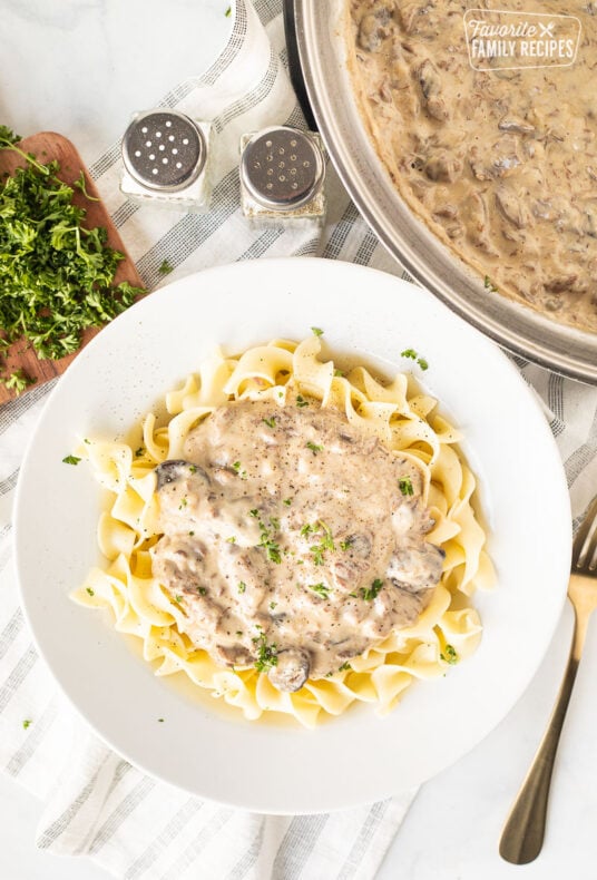 Pot of Easy Beef Stroganoff next to a plate of Beef Stroganoff over noodles.