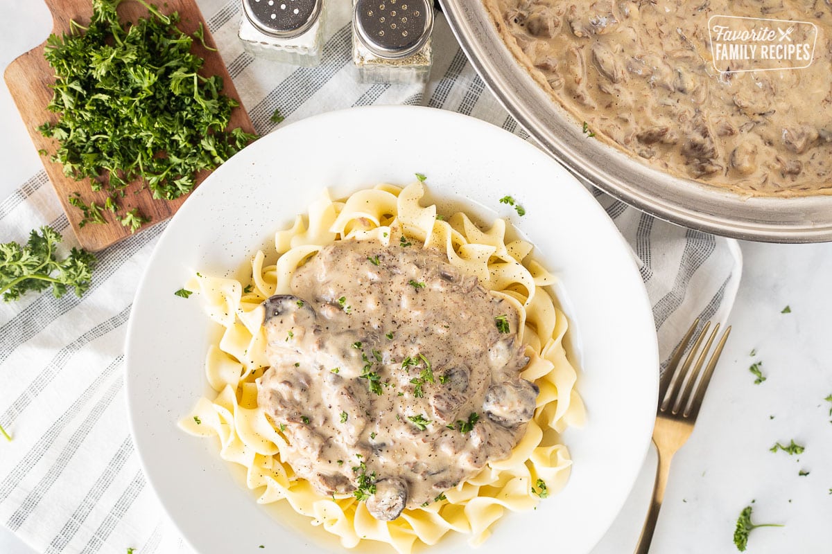 Plate of Easy Beef Stroganoff over noodles. Parsley on the side and garnished on top.